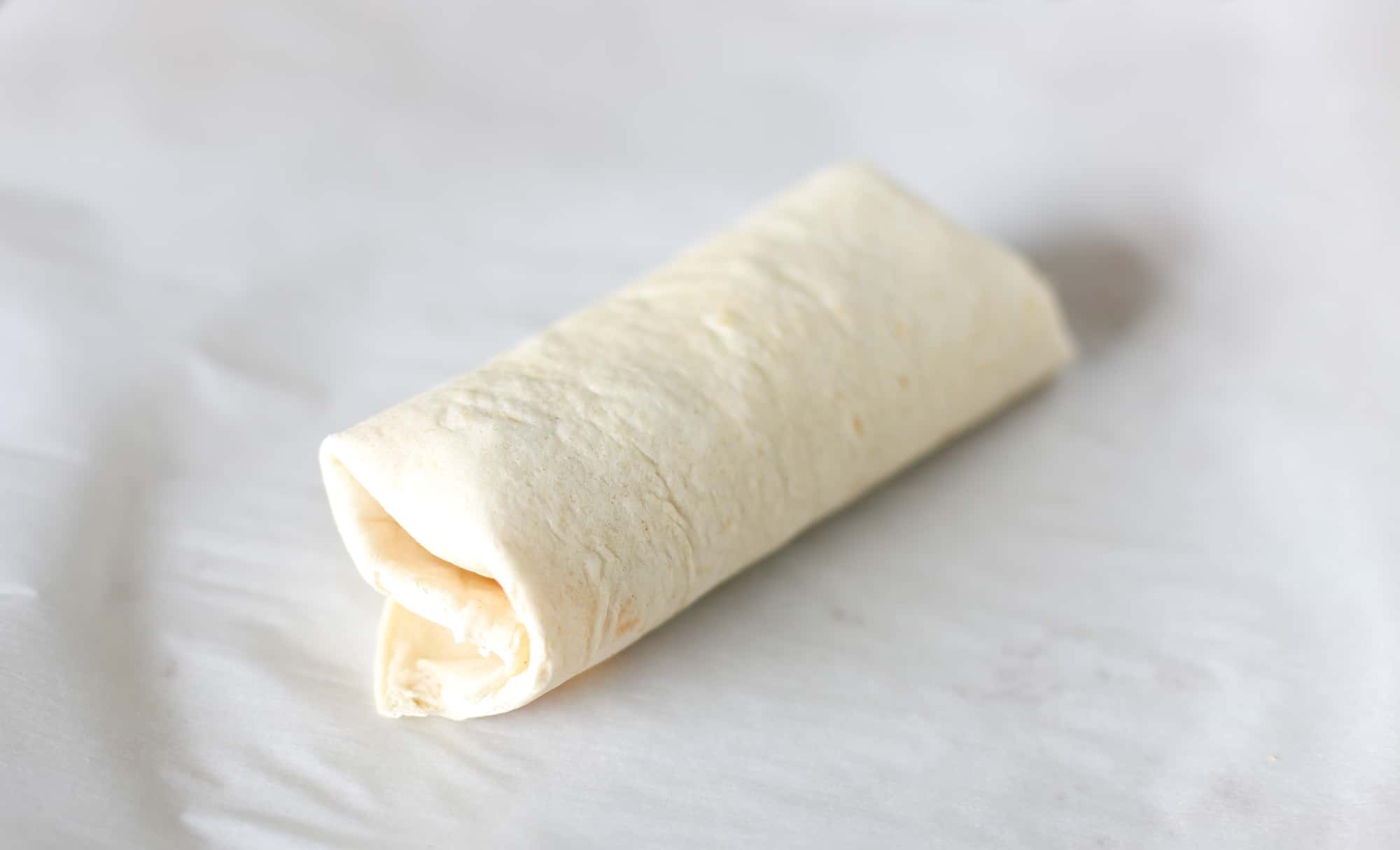 A burrito rolled up and ready to be baked.