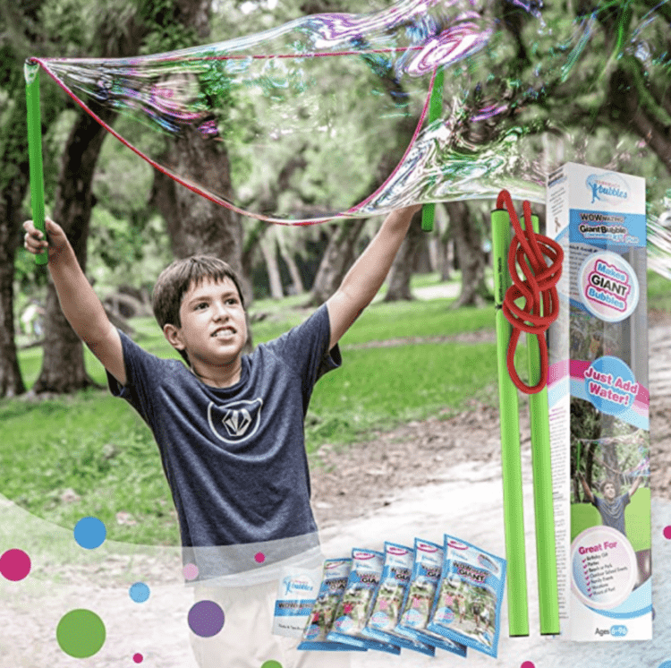 A kid making a giant bubble with an inset photo a Giant Bubble kit.