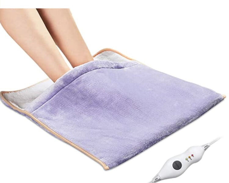 Two feet inside a lavender-colored heating pad that doubles as a foot warmer.