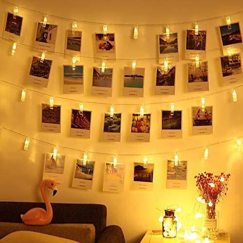 LED strings of lights on a wall with clips holding photos.