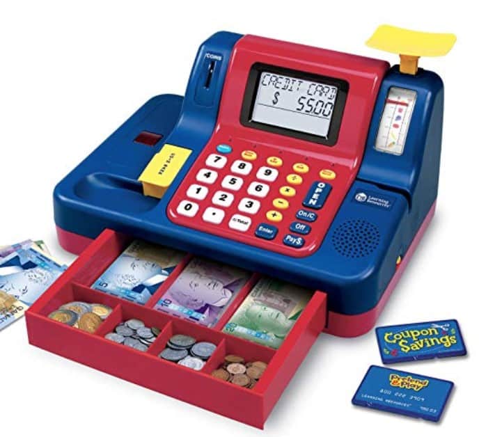 Red and blue toy cash register with the drawer open and play money in the drawer and next to the cash register.