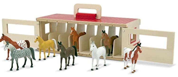 Horse farm wooden toy that has stalls with play horses in them and in front of them.