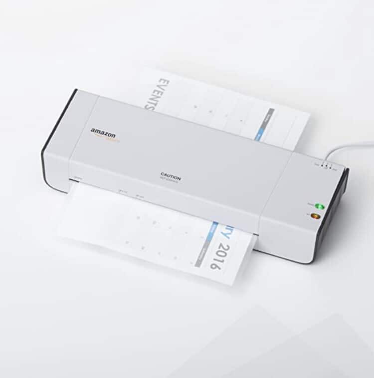 A small personal size laminator with a calendar page going through it.