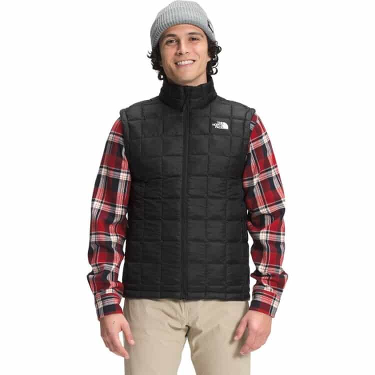 A man wearing a red flannel with a black North Face vest over it.