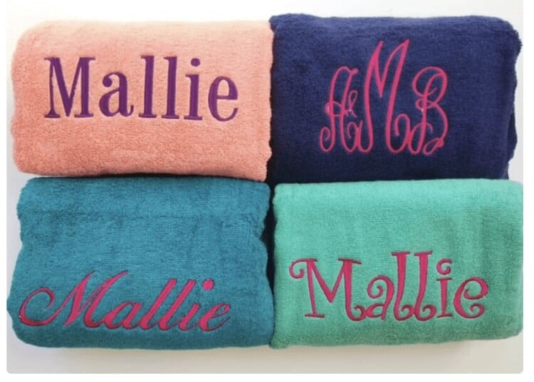 Four different colors of towels with the name "Mallie" embroidered in different fonts.