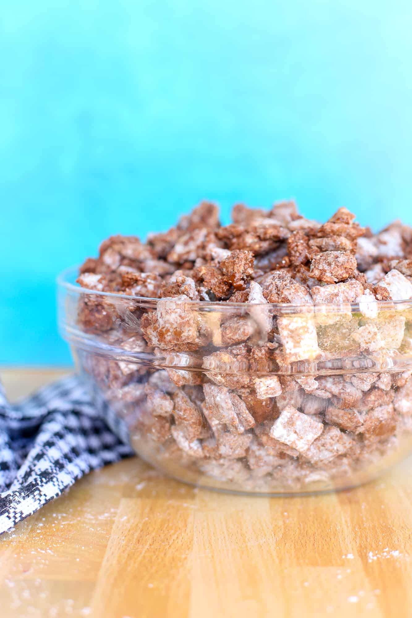 Puppy chow in a glass bowl on a counter.