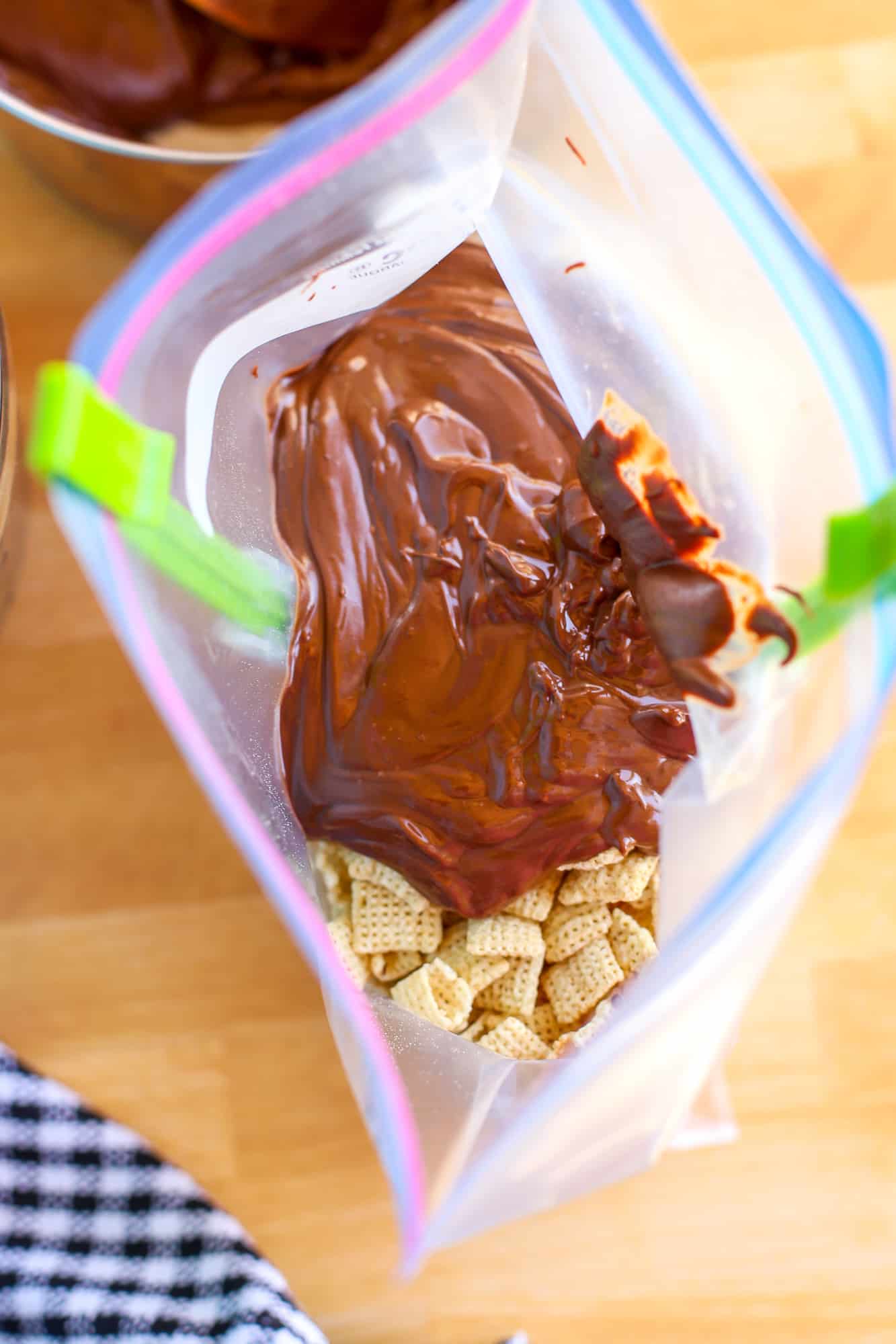 Chex cereal in a gallon-size plastic baggie with melted chocolate peanut butter poured on top to be mixed.