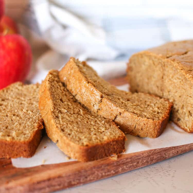 Applesauce bread on a platter with a few slices lying in front of the loaf.