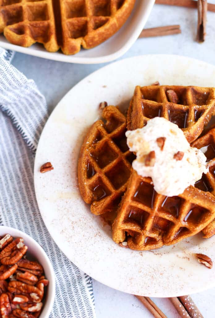 Whole wheat pumpkin waffle on a plate with whipped cream
