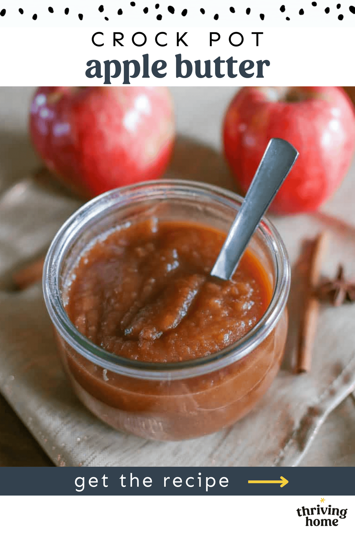 A small jar of homemade apple butter with more apples and cinnamon sticks around it.