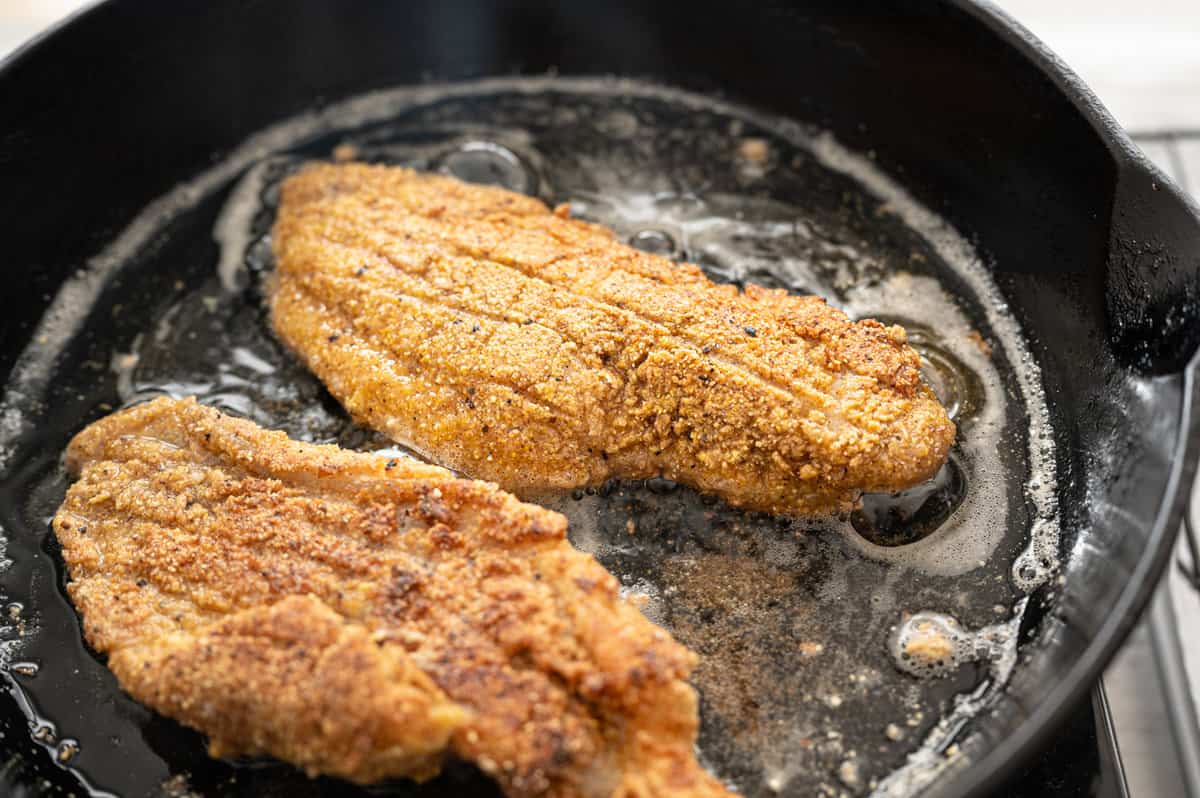 Fried catfish in a cast iron skillet in hot oil.