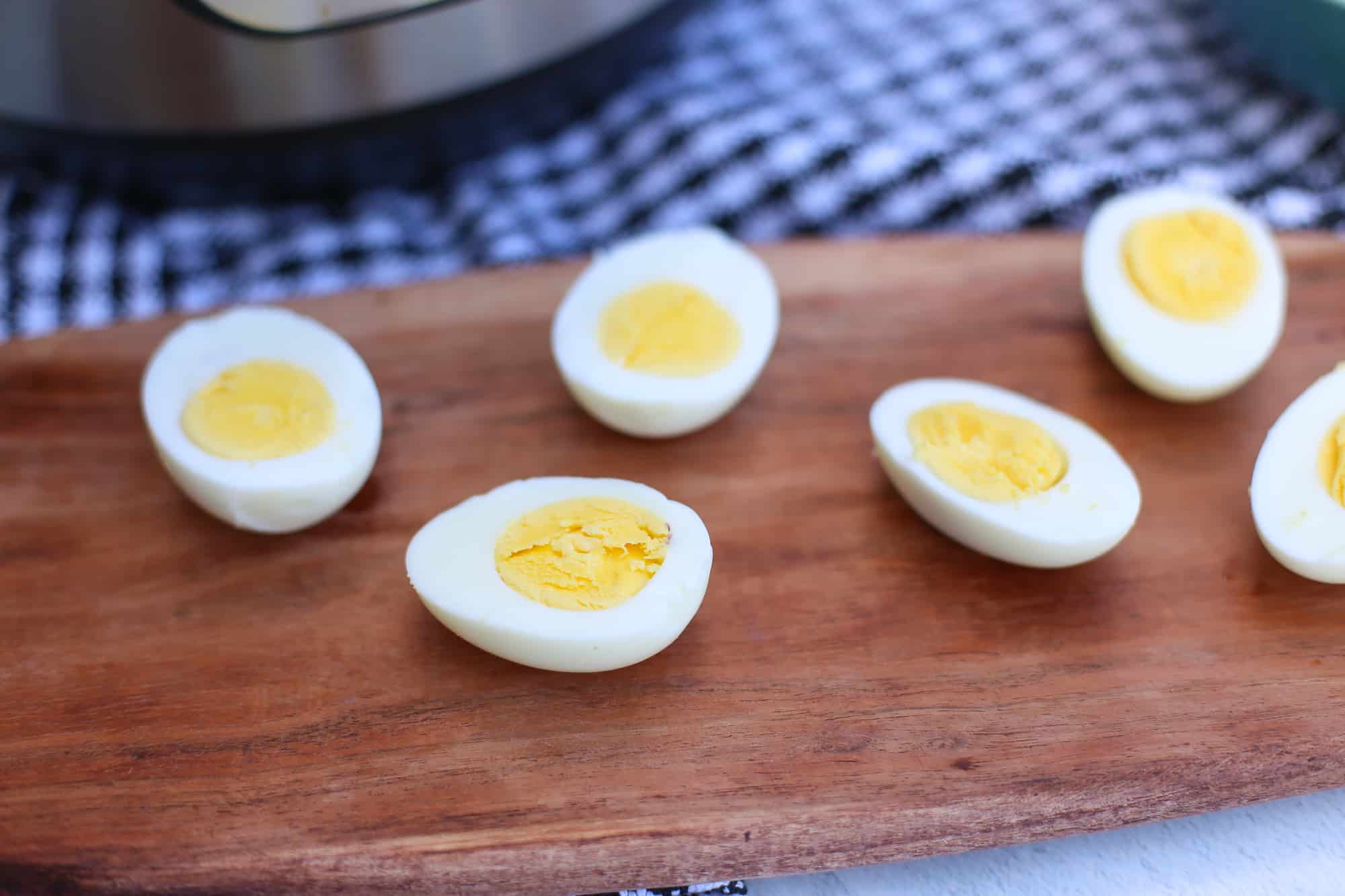 Hard-boiled eggs sliced in half and lined up on a wooden serving tray.