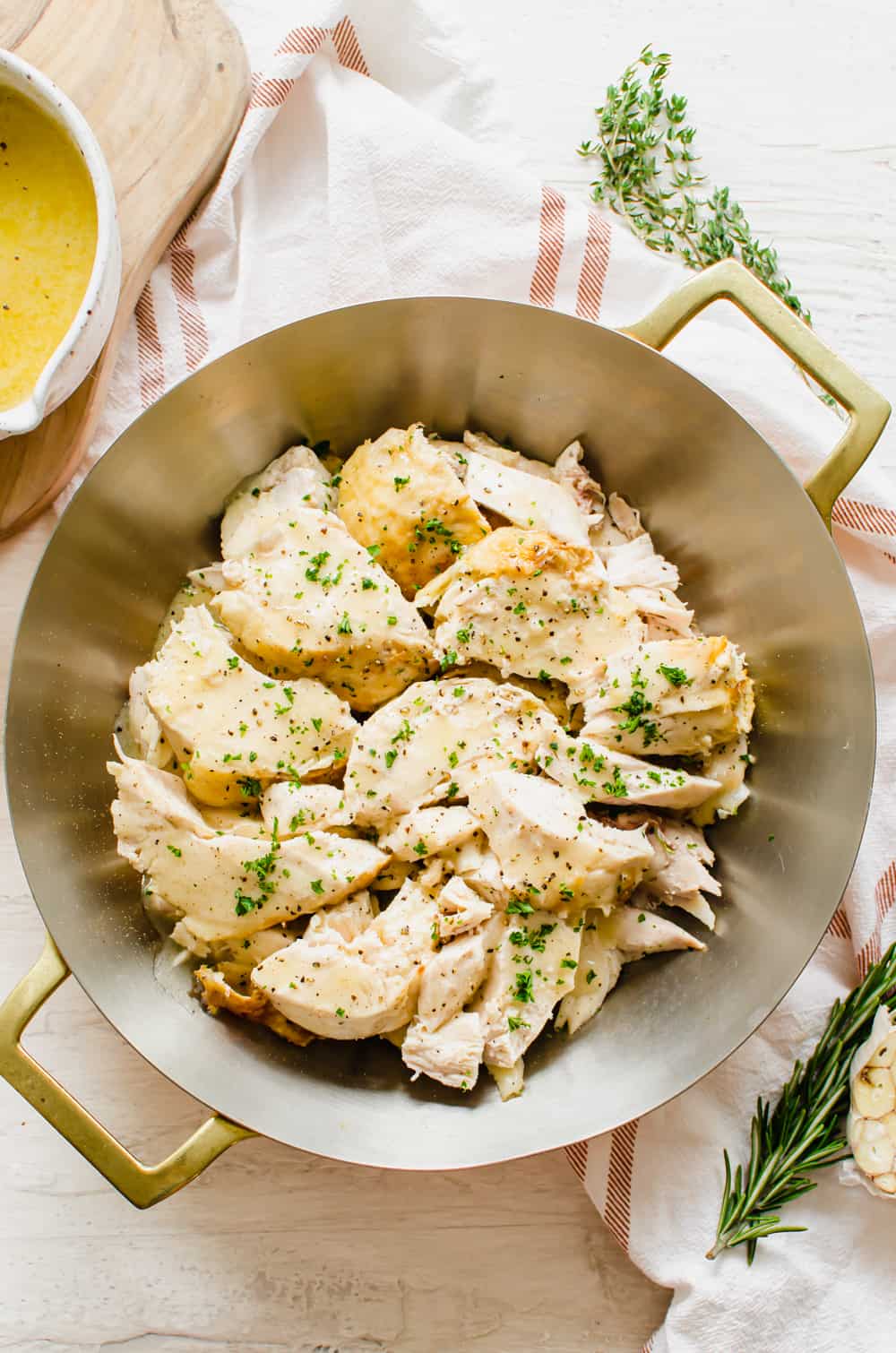 Sliced whole chicken on a serving platter with chopped parsley sprinkled on top.