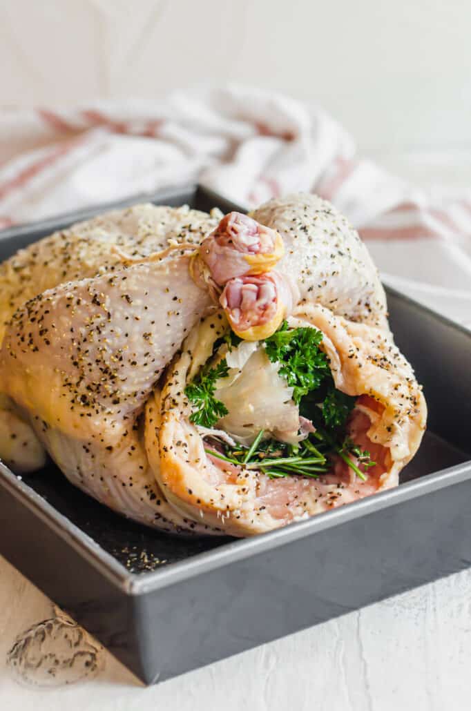 raw, seasoned whole chicken stuffed with herbs and vegetables