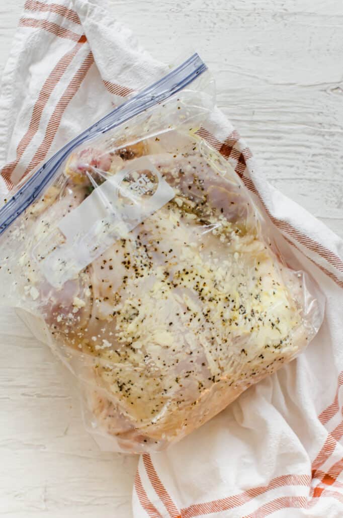whole chicken with seasoning in a freezer bag