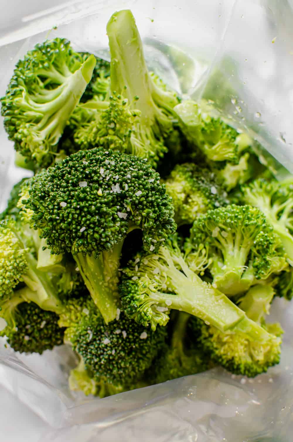 Broccoli florets being tossed with olive oil and salt.