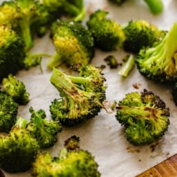 Roasted broccoli on a baking sheet covered with parchment paper.