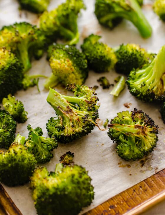 Roasted broccoli on a baking sheet covered with parchment paper.