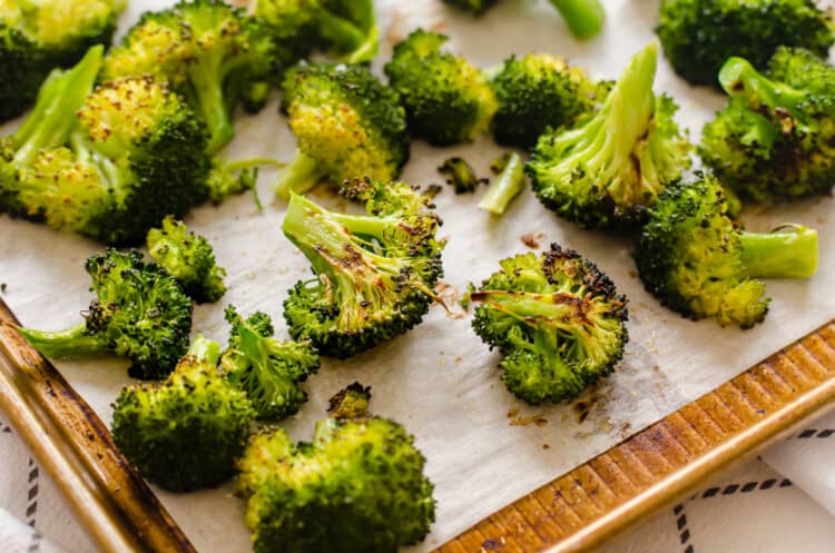 Roasted broccoli on a baking sheet lined with parchment paper.