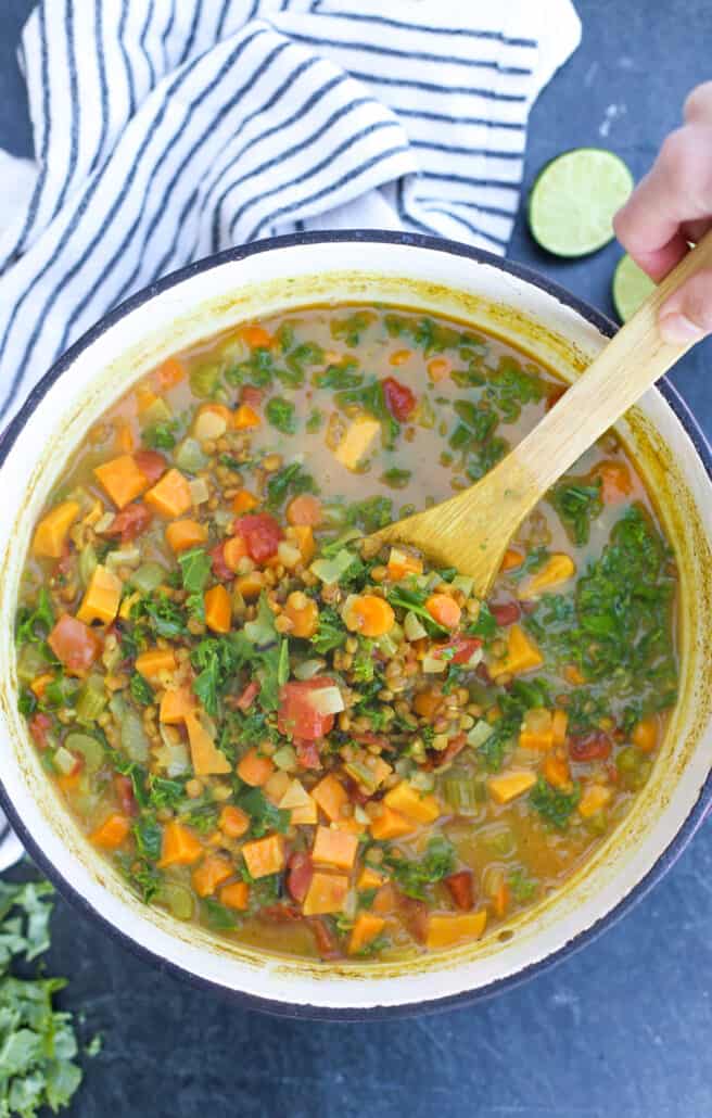 Coconut Curry Lentil Soup in dutch over with wooden spoon