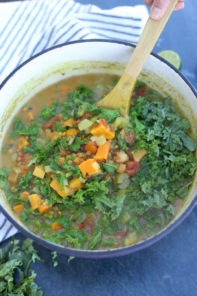 stirring chopped kale into vegetable soup