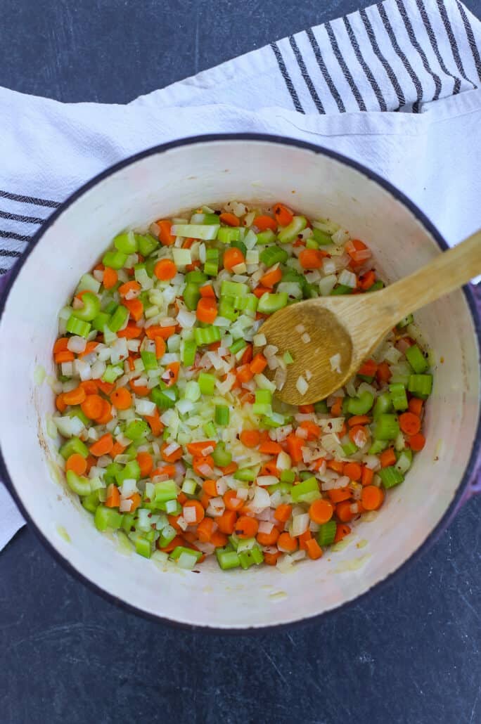 Sauteed veggies in dutch oven pot with wooden spoon
