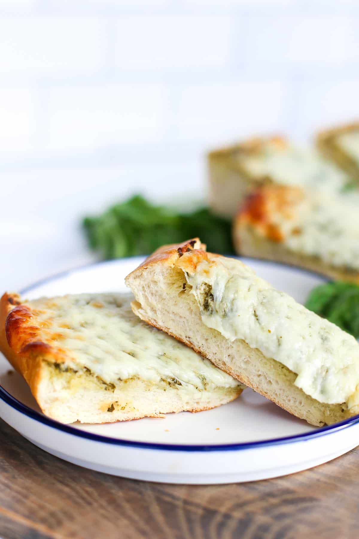 Two pieces of pesto bread on a plate.