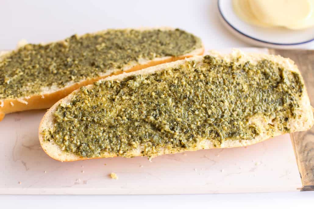 French loaf of bread with pesto spread over it