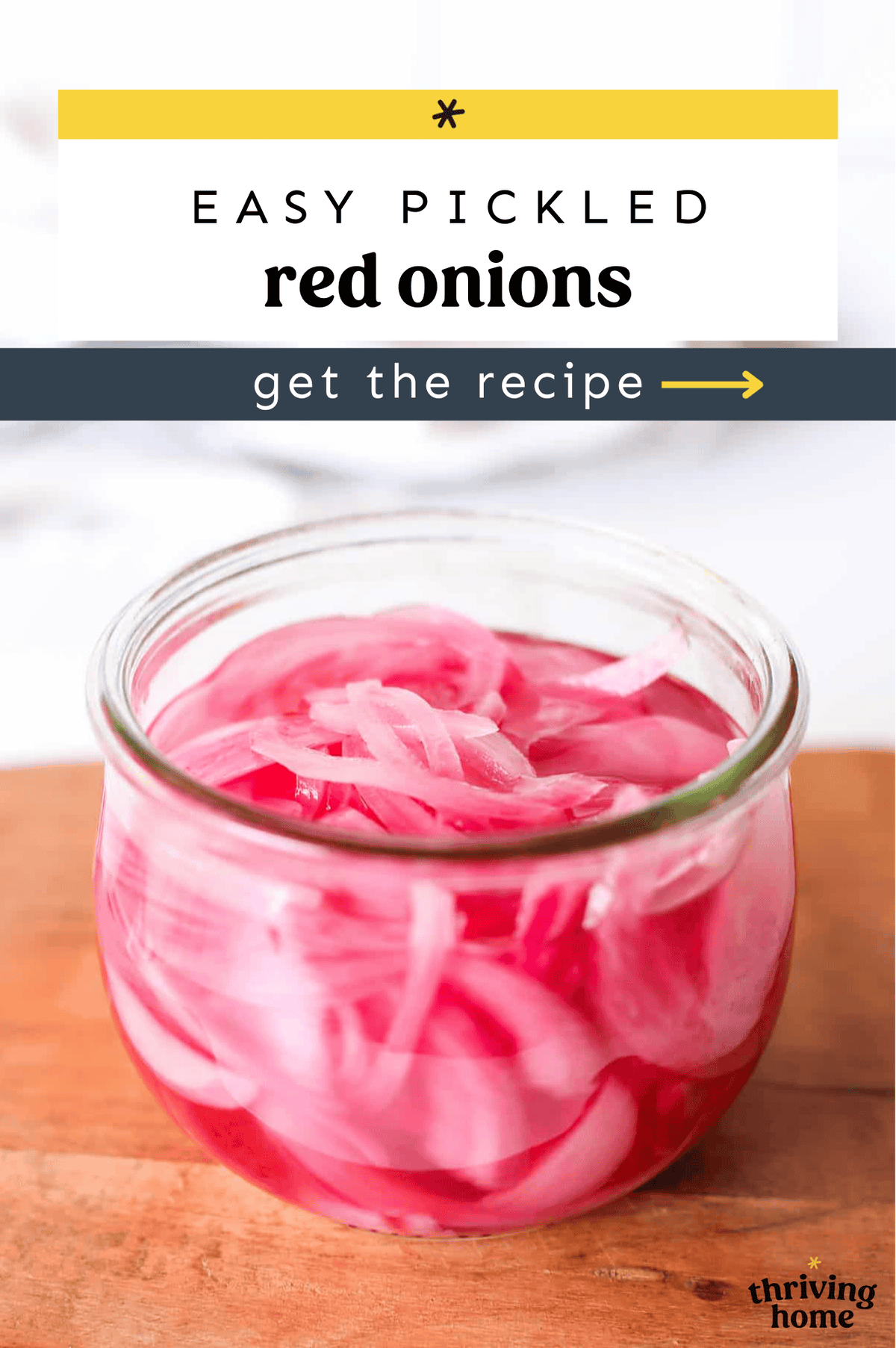 Homemade pickled red onion in a small jar on a wooden cutting board.