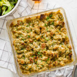 Chicken and stuffing casserole baked in a glass 8x8 pan on the table with bowl of steamed broccoli in the background.