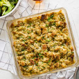 Chicken and stuffing casserole baked in a glass 8x8 pan on the table with bowl of steamed broccoli in the background.