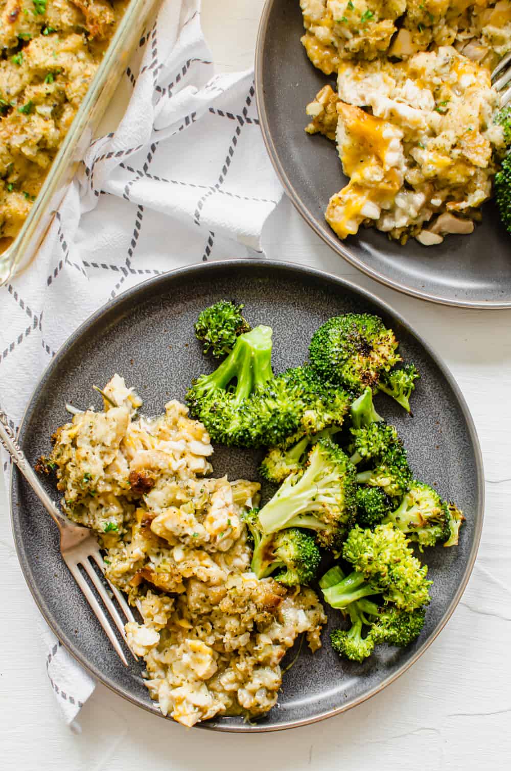 A plate with cheesy chicken and stuffing casserole and roasted broccoli.