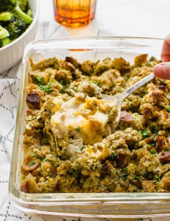 A spoon serving chicken stuffing casserole out of a glass casserole dish.