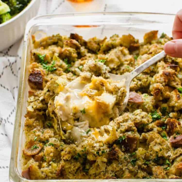 A spoon serving chicken stuffing casserole out of a glass casserole dish.