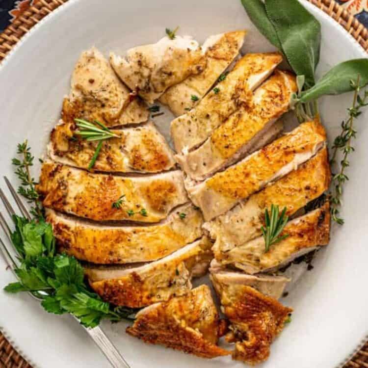 carved turkey breast on a serving platter with gravy on the side