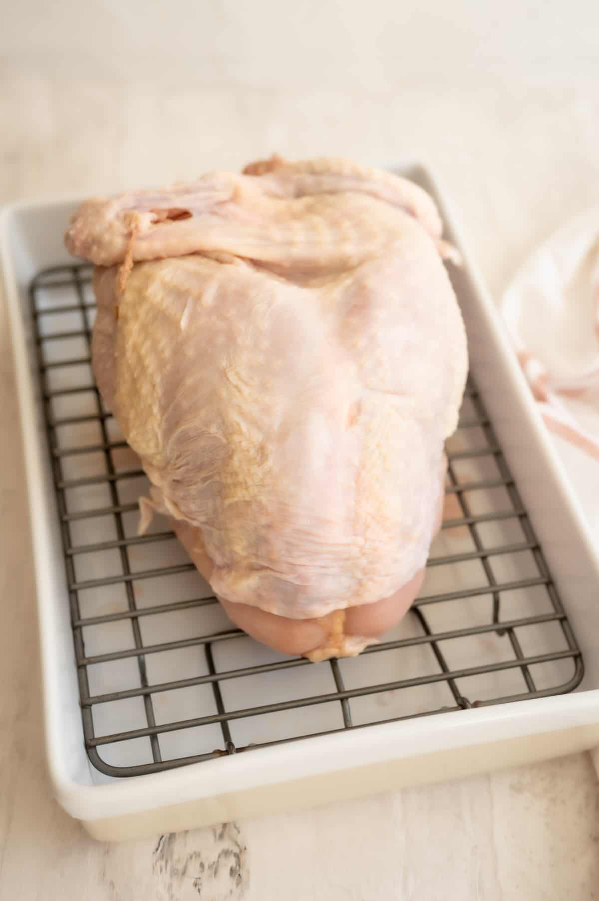 Bone-in turkey breast on a rack in a white roasting dish.