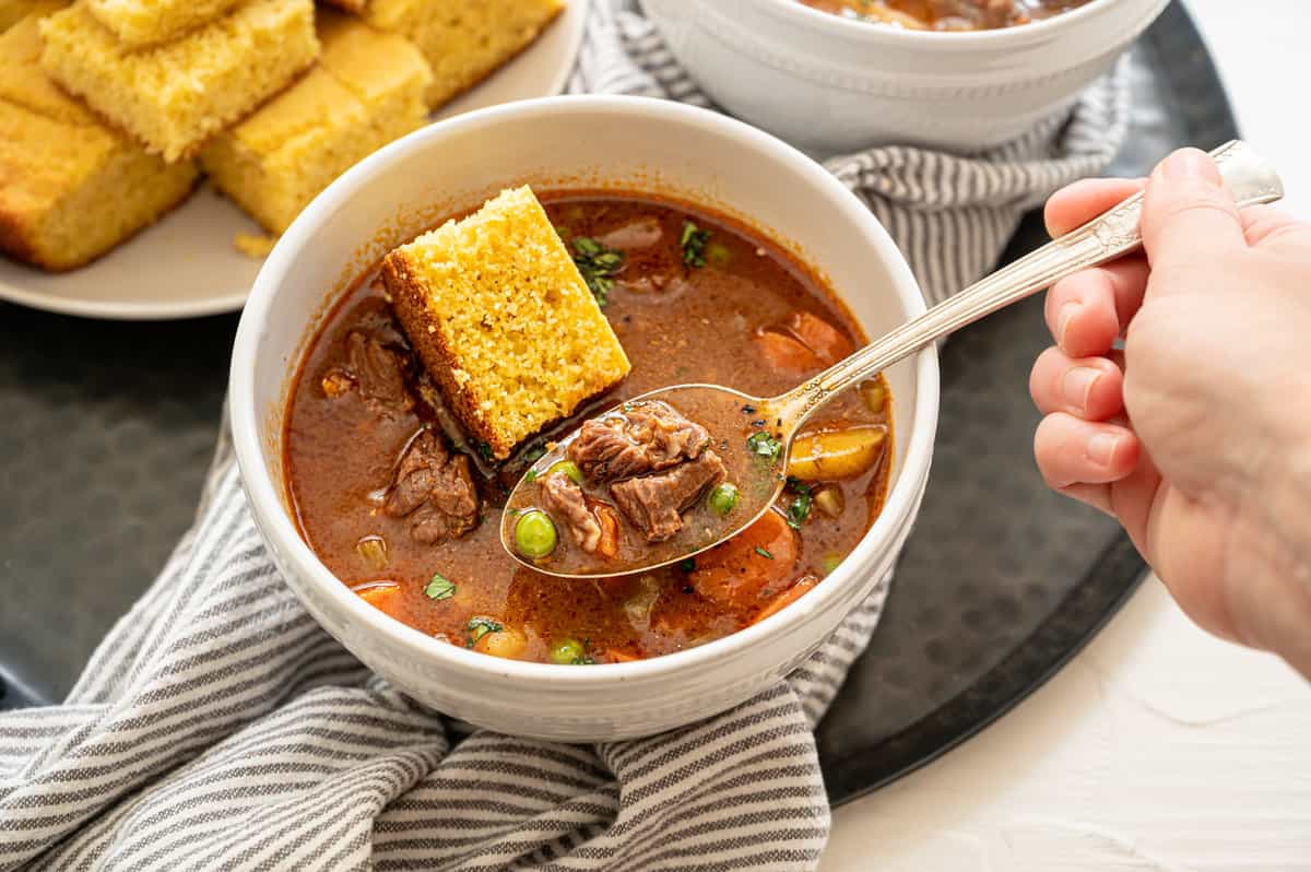 Instant Pot Beef Stew in a bowl with a piece of cornbread.