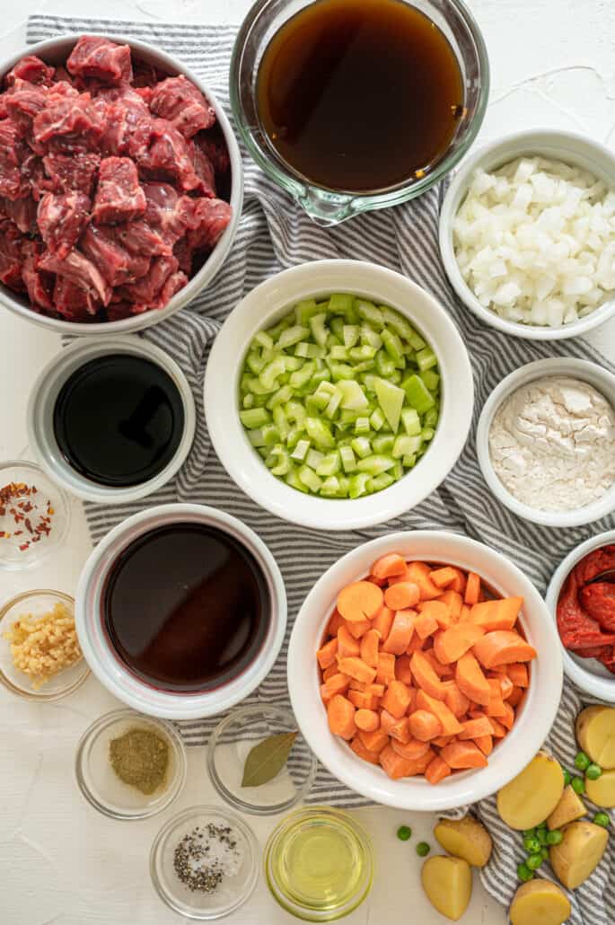 ingredients for beef stew in separate bowls on a counter