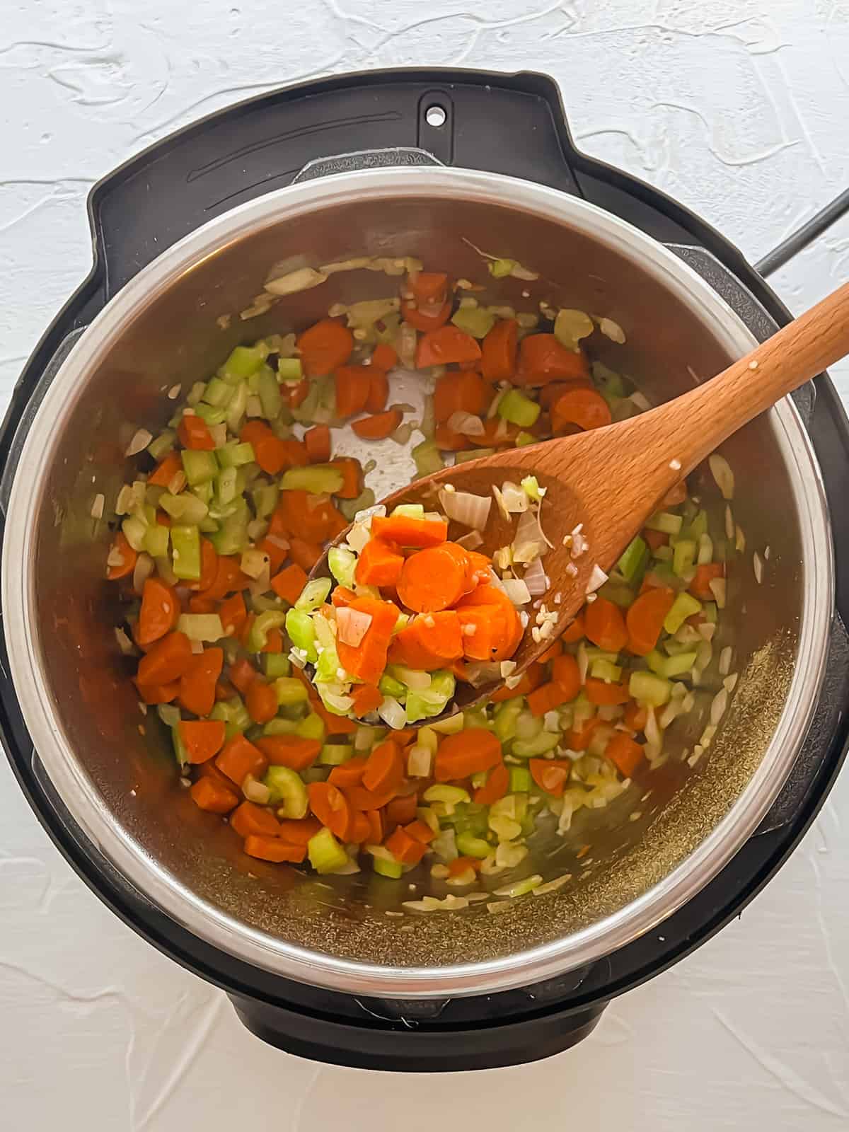 Carrots, celery, onions, and garlic sauteing in an Instant Pot.