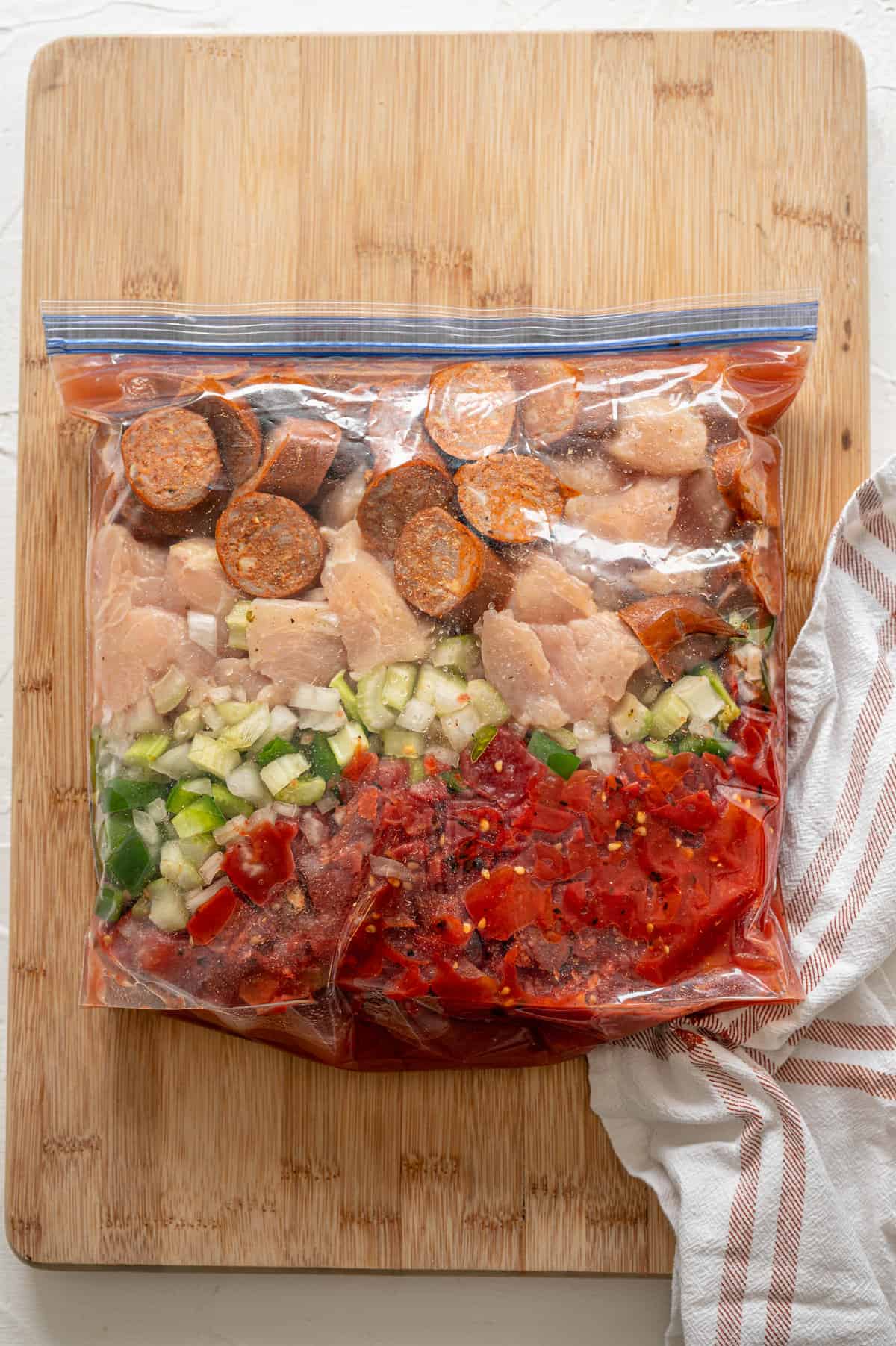 Raw jambalaya ingredients layered in a freezer bag.