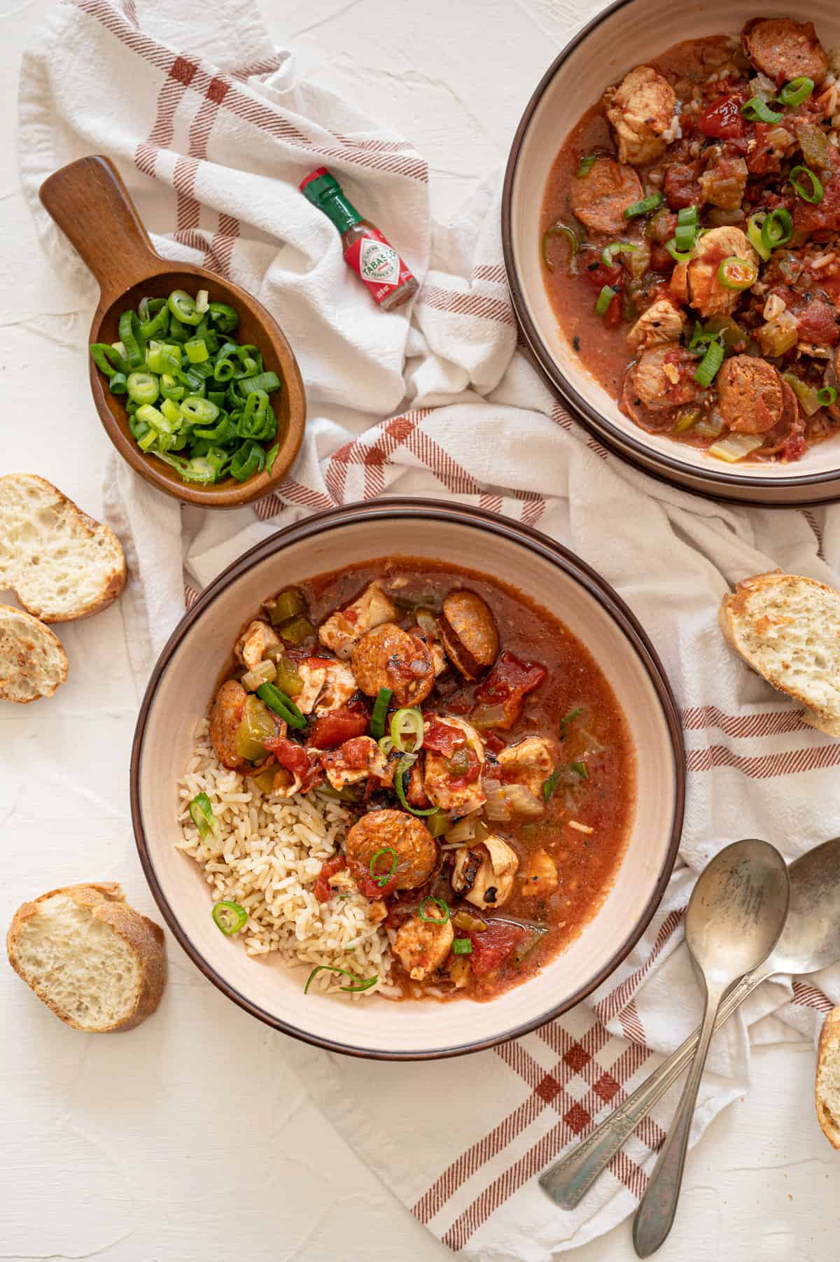 Instant Pot Jambalaya in a bowls with spoons and bread on the side.