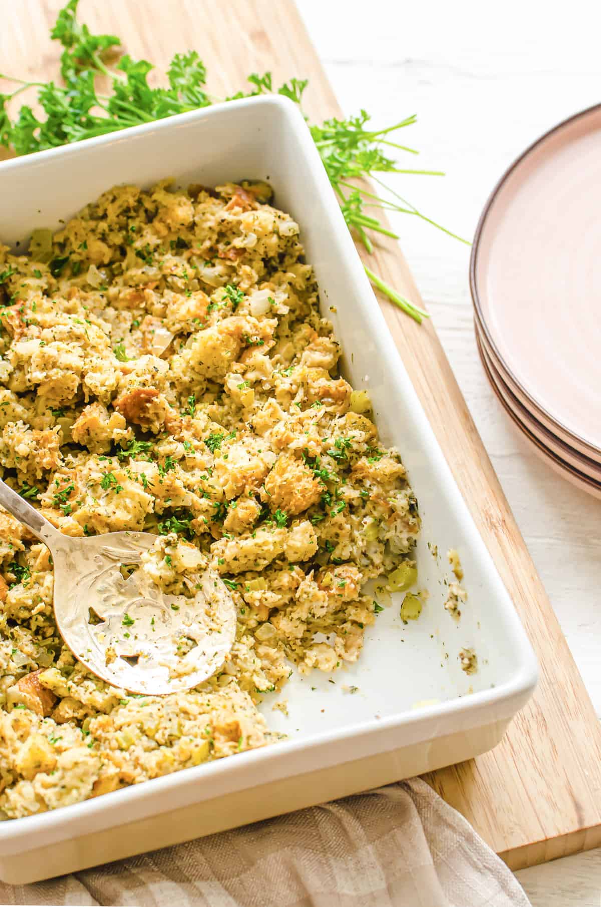 Homemade stuffing in a white casserole dish with a serving missing.