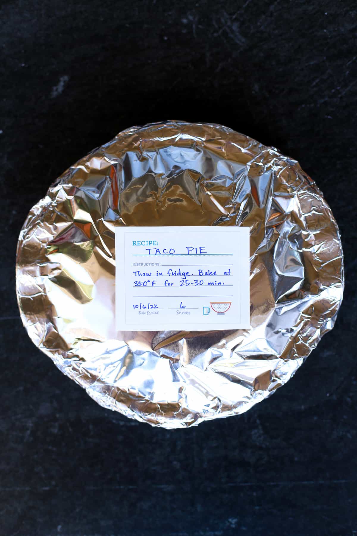 A foil-covered pie dish labeled taco pie for the freezer.
