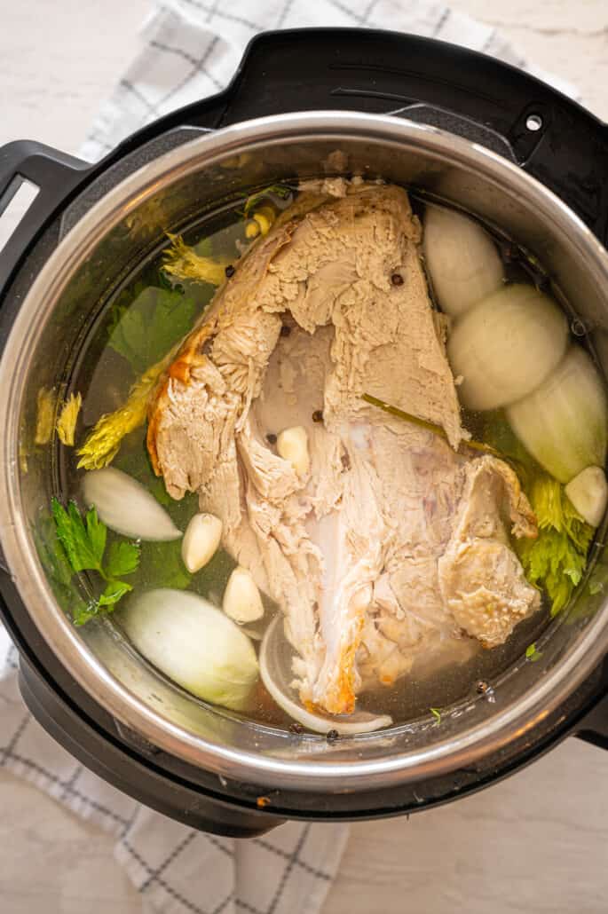 overhead shot of turkey carcass, vegetables, and water in Instant Pot to make broth