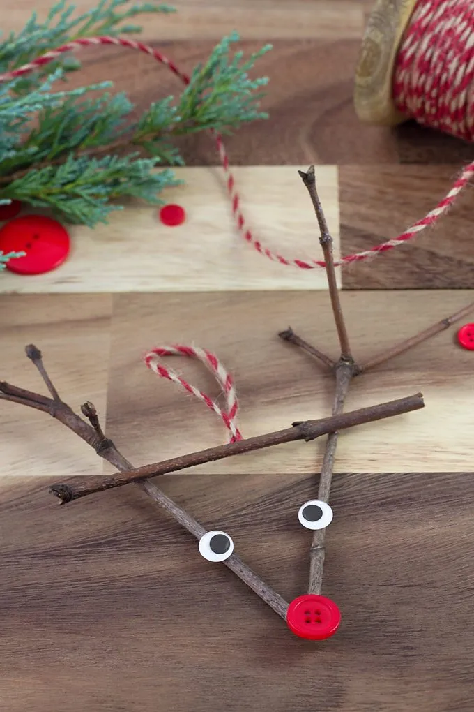 Reindeer made out of twigs with googly eyes and a red button nose.