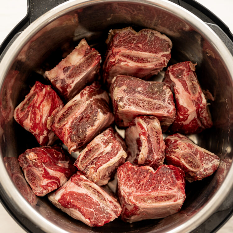 Four-inch beef short ribs standing on end in an Instant Pot.