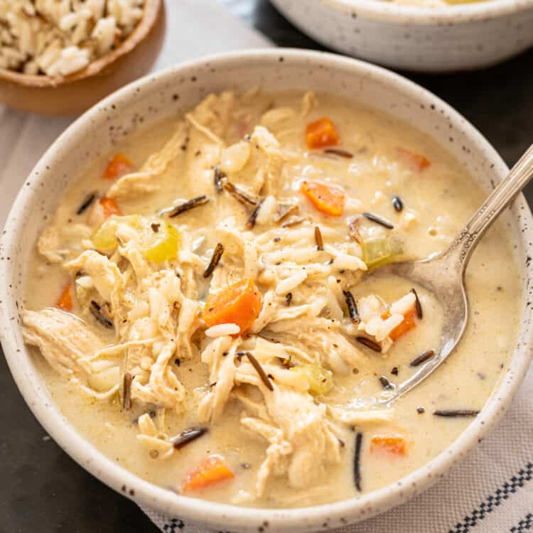 Chicken and wild rice soup in a white bowl with a spoon.