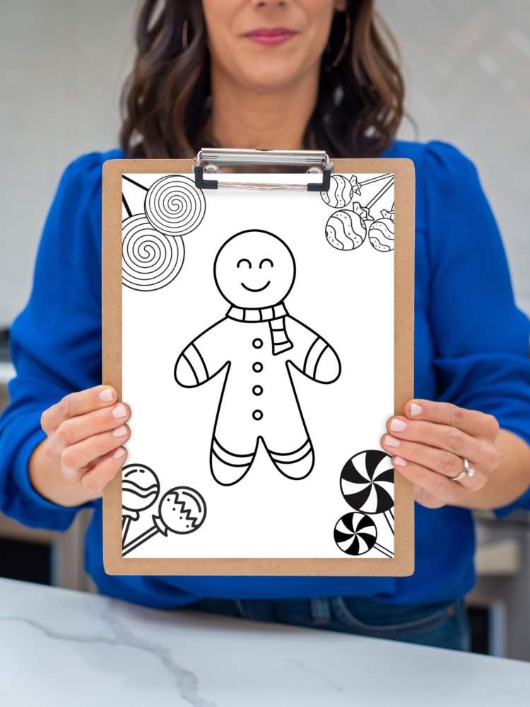 Person holding a clipboard with a gingerbread man coloring page on it.
