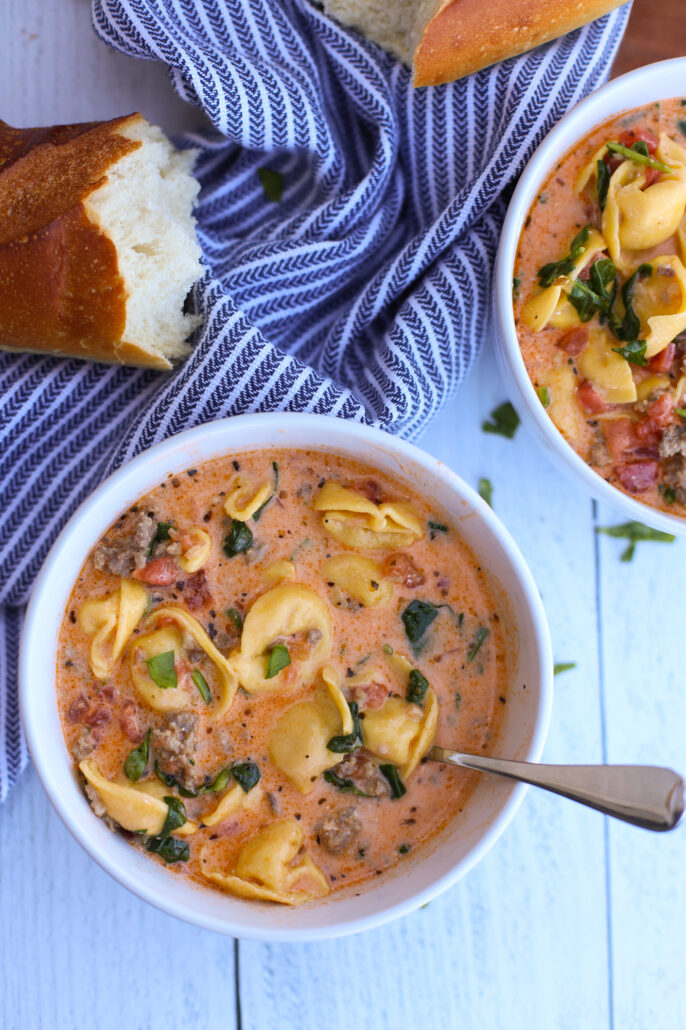 Sausage and tortellini soup in a white bowl
