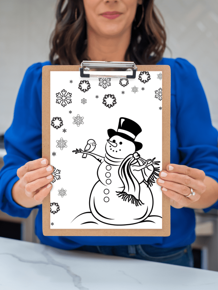 Hands holding a snowman coloring page on a clipboard.